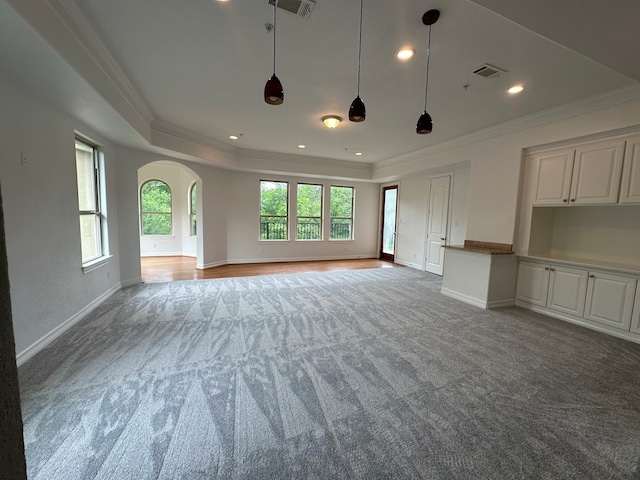 unfurnished living room featuring crown molding, light wood-type flooring, and a tray ceiling