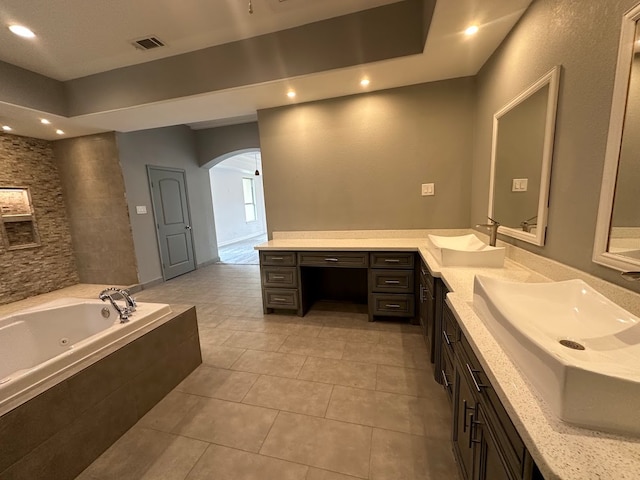 bathroom with tiled tub, tile flooring, and vanity