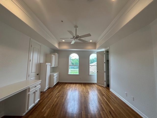 unfurnished living room with a tray ceiling, ceiling fan, dark hardwood / wood-style floors, and crown molding