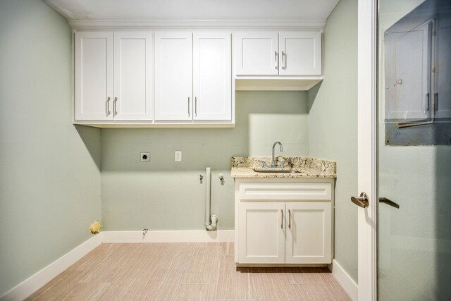 clothes washing area featuring hookup for an electric dryer, light tile floors, cabinets, and sink