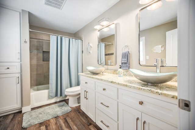 full bathroom with shower / bath combo with shower curtain, toilet, double vanity, and wood-type flooring