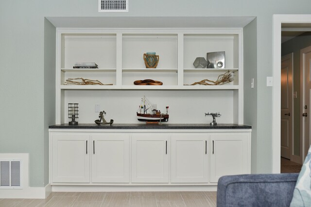 bar featuring white cabinets and dark stone counters