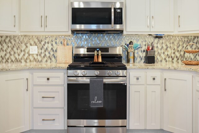 kitchen with appliances with stainless steel finishes, backsplash, and white cabinets