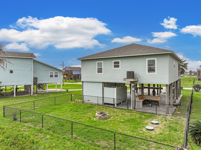 back of property featuring cooling unit, a fire pit, and a lawn