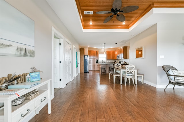 dining room with ceiling fan, a raised ceiling, dark wood-type flooring, and wooden ceiling