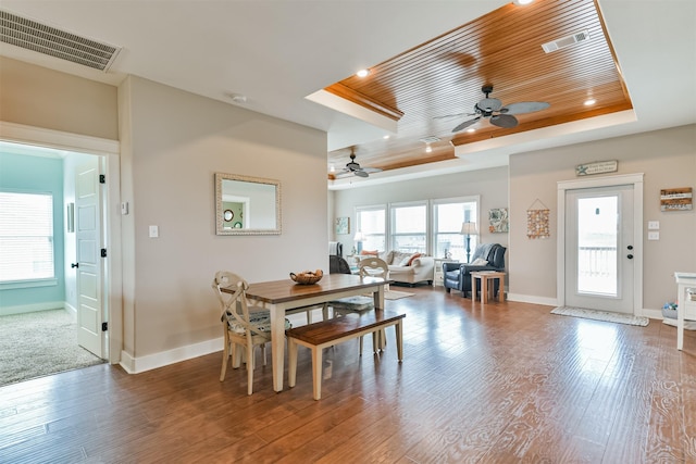 dining room featuring hardwood / wood-style flooring, ceiling fan, a tray ceiling, and wood ceiling