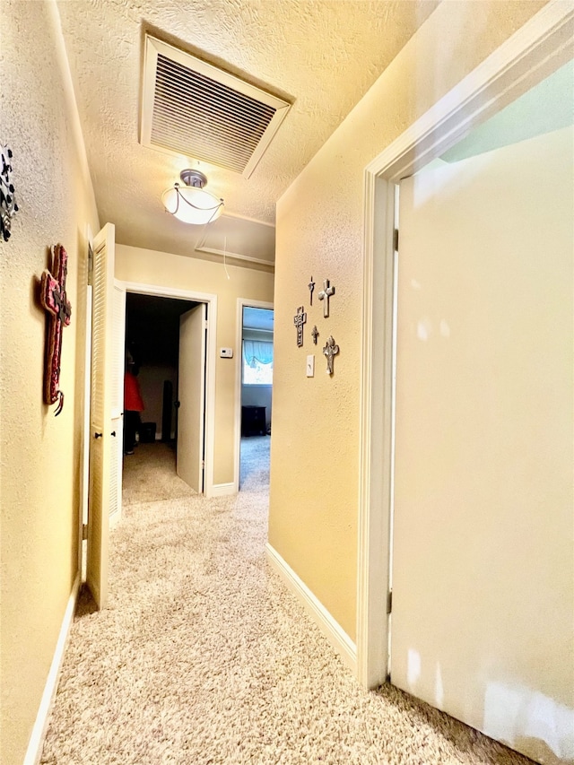 hall with a textured ceiling and light carpet