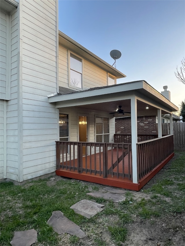 back house at dusk with a deck and ceiling fan