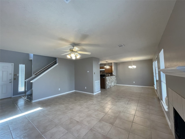 unfurnished living room with light tile flooring and ceiling fan with notable chandelier