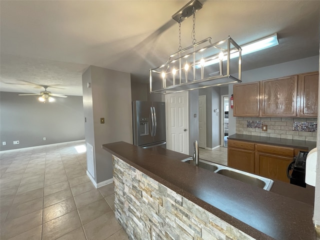 kitchen featuring tasteful backsplash, light tile floors, stainless steel fridge with ice dispenser, ceiling fan with notable chandelier, and hanging light fixtures