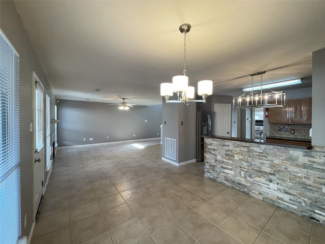 kitchen with backsplash, ceiling fan with notable chandelier, pendant lighting, and light tile floors