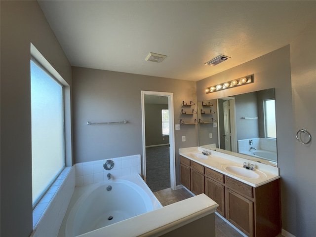 bathroom with a bath to relax in, double sink vanity, and tile flooring