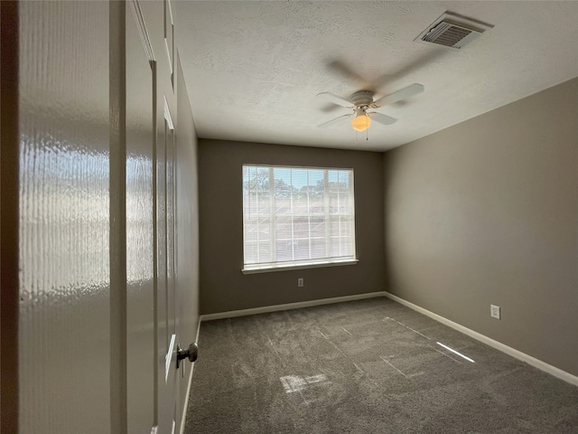 spare room featuring a textured ceiling, ceiling fan, and dark colored carpet