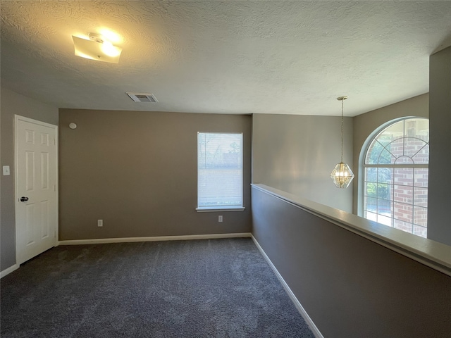 empty room featuring a textured ceiling and dark carpet