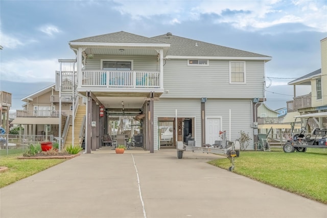 back of house with a carport, a balcony, and a lawn