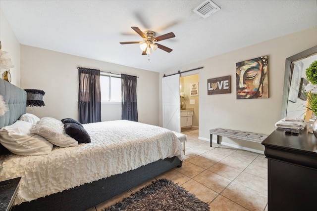 tiled bedroom with ceiling fan, ensuite bathroom, and a barn door