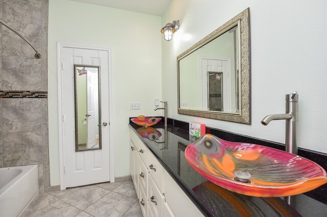 bathroom featuring dual bowl vanity, tiled shower / bath combo, and tile flooring