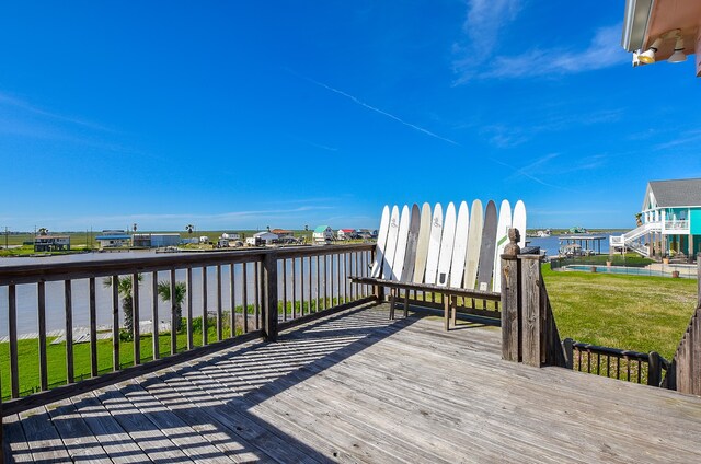 wooden terrace with a water view and a yard