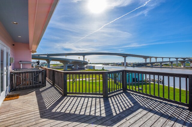 deck with a water view and a lawn