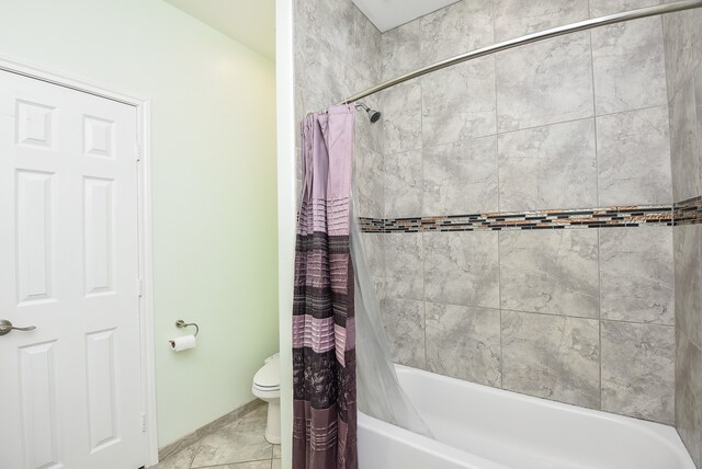 bathroom with tile flooring, toilet, and shower / tub combo with curtain