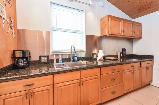 kitchen featuring sink, light tile flooring, wood ceiling, vaulted ceiling, and dark stone countertops