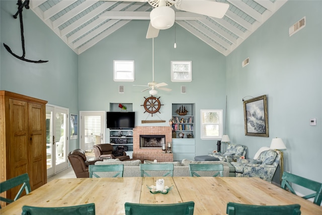 dining space with high vaulted ceiling, a tile fireplace, a wealth of natural light, and ceiling fan