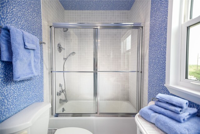 bathroom featuring bath / shower combo with glass door and toilet