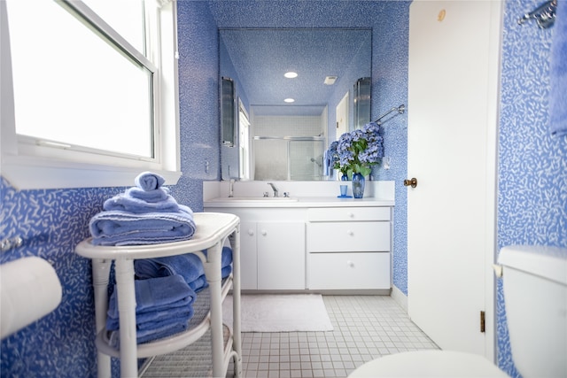 bathroom with a textured ceiling, toilet, vanity with extensive cabinet space, and tile floors