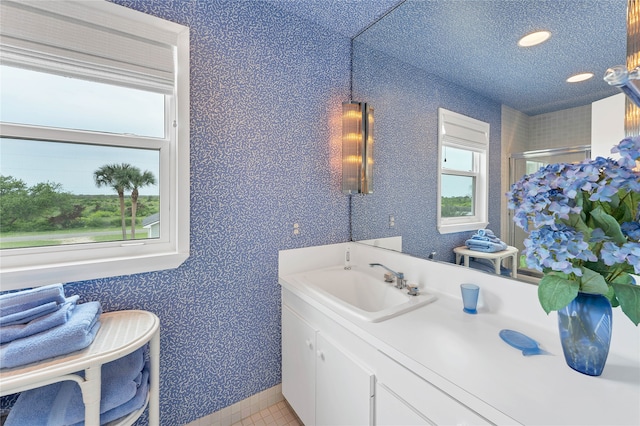 bathroom featuring a textured ceiling, tile flooring, vanity, and plenty of natural light