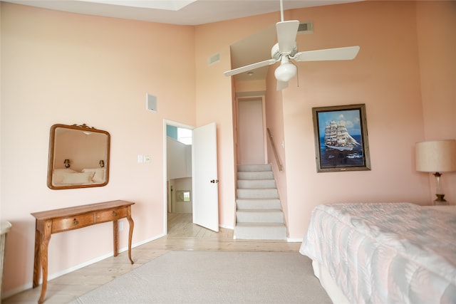 bedroom featuring ceiling fan, a high ceiling, and light hardwood / wood-style flooring