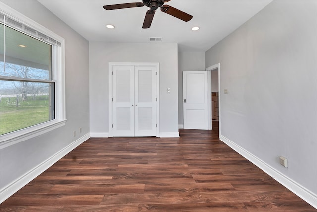 unfurnished bedroom with dark hardwood / wood-style flooring, ceiling fan, and a closet