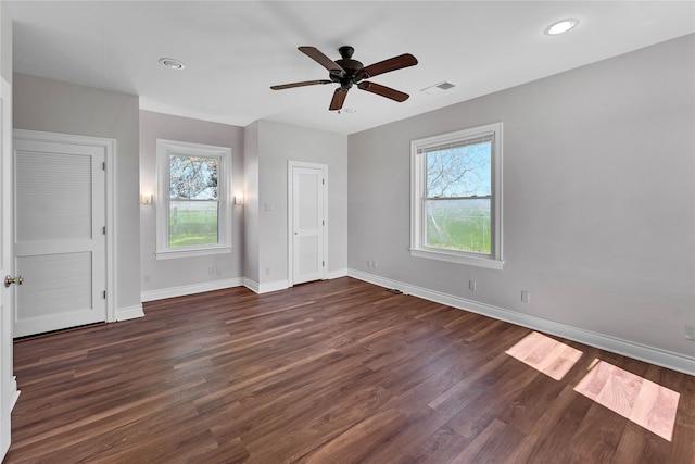 spare room featuring ceiling fan, dark hardwood / wood-style floors, and a healthy amount of sunlight