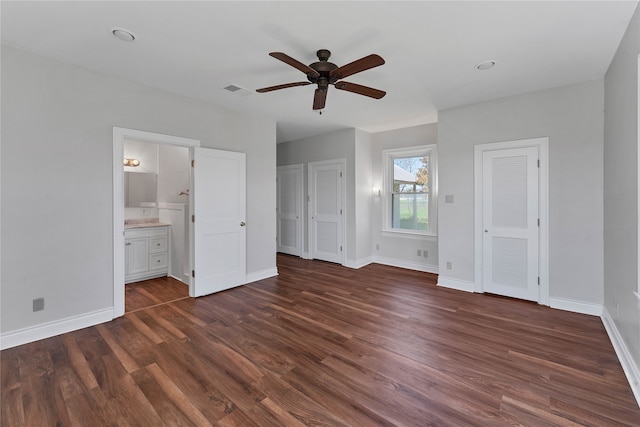 unfurnished bedroom featuring ceiling fan, two closets, dark hardwood / wood-style floors, and connected bathroom