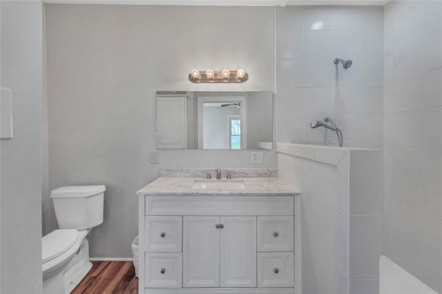 bathroom featuring large vanity, tiled shower, toilet, and hardwood / wood-style flooring