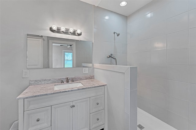 bathroom featuring ceiling fan, tiled shower, and vanity