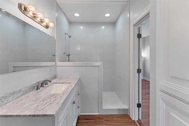 bathroom featuring tiled shower, wood-type flooring, and vanity