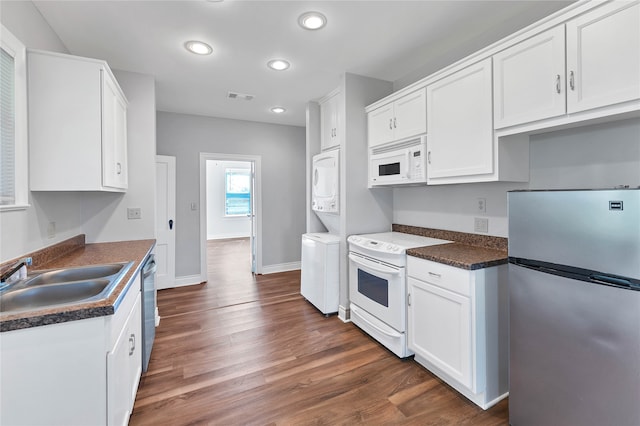 kitchen featuring appliances with stainless steel finishes, stacked washer / drying machine, white cabinetry, and dark hardwood / wood-style floors