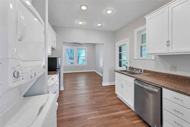 kitchen featuring dark wood-type flooring, white cabinets, dishwasher, stacked washer / drying machine, and sink