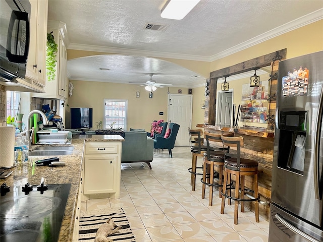 kitchen featuring light stone countertops, ceiling fan, a textured ceiling, ornamental molding, and stainless steel fridge with ice dispenser