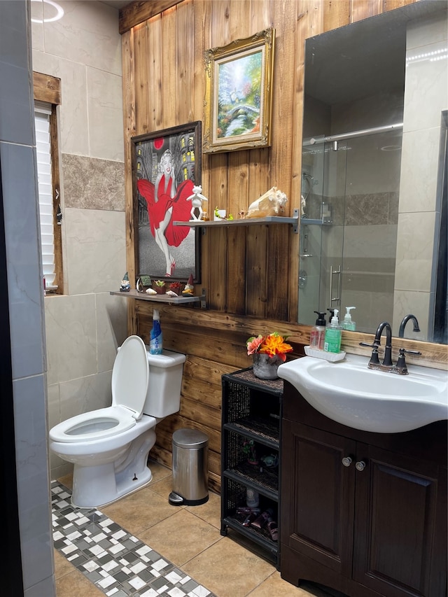 bathroom with tile flooring, tile walls, a shower with door, vanity, and toilet