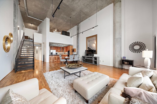 living room featuring light wood-type flooring and a towering ceiling