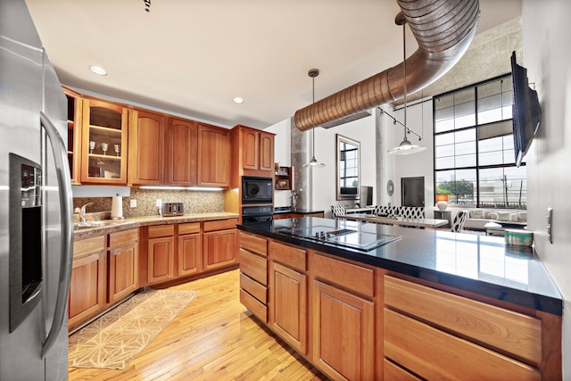 kitchen with light hardwood / wood-style floors, sink, black appliances, backsplash, and hanging light fixtures