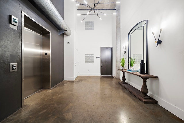 foyer with a notable chandelier, a towering ceiling, and elevator