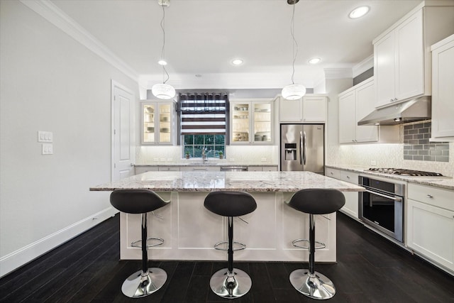 kitchen featuring stainless steel appliances, light stone countertops, a center island, and pendant lighting