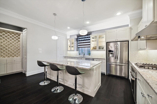 kitchen with appliances with stainless steel finishes, pendant lighting, white cabinetry, a center island, and light stone countertops