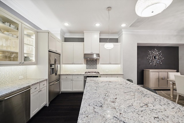 kitchen with dark wood-type flooring, appliances with stainless steel finishes, white cabinetry, hanging light fixtures, and light stone counters