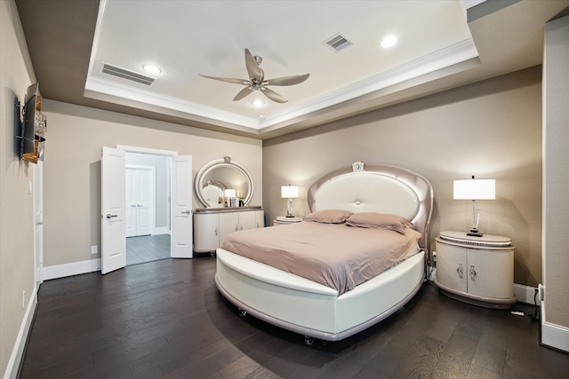 bedroom featuring dark wood-type flooring, a tray ceiling, and crown molding