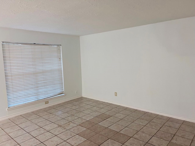 tiled spare room featuring a textured ceiling