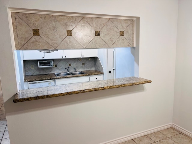 kitchen featuring backsplash, sink, dark stone countertops, and light tile floors