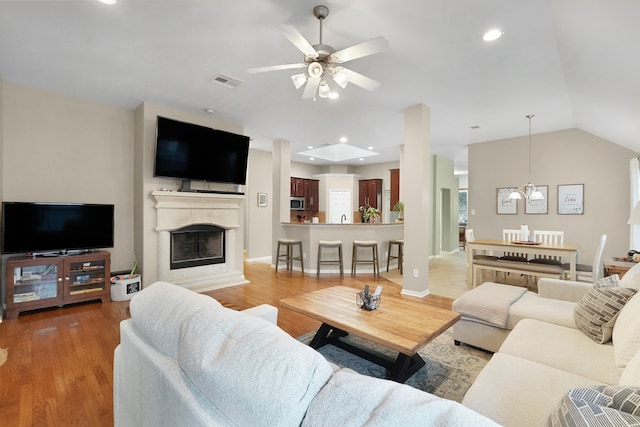 living room featuring ceiling fan with notable chandelier, light hardwood / wood-style flooring, sink, and lofted ceiling